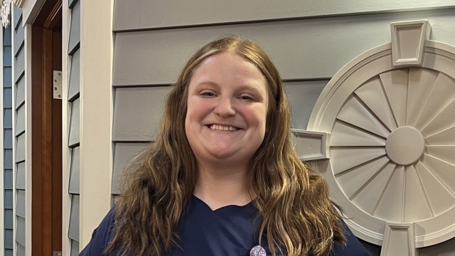 Woman standing in front of a wall smiling