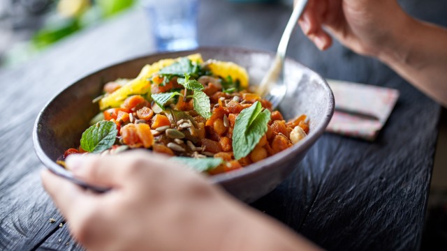 Hands holding a fork and a healthy bowl of salad
