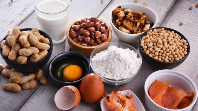 Several bowls of single ingredient foods, a glass of milk and a broken eggshell on the table