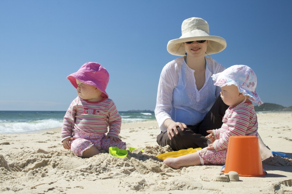 Mother and two children sitting on sand at the beach
