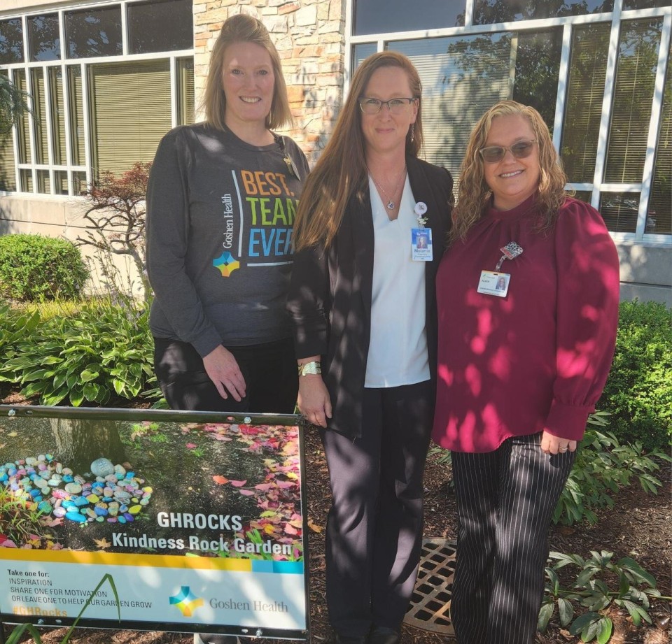 Three ladies standing in a rock garden in front of a building v2