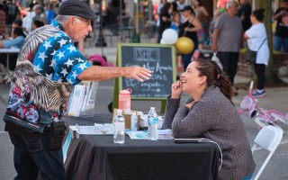 Man standing in front of a table talking to a woman sitting behind the table