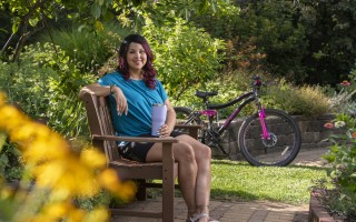 Woman sitting on a park bench with a bike in the background