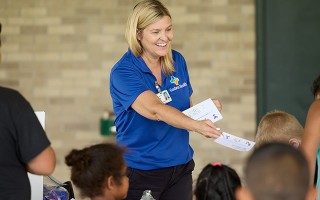 Instructor handing out leaflets to children
