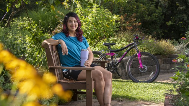 Woman sitting on a park bench with a bike in the background