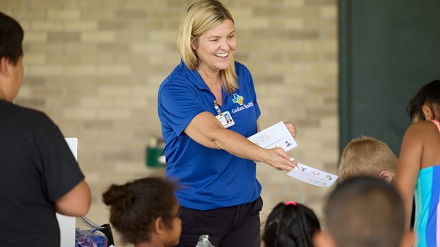 Instructor handing out leaflets to children