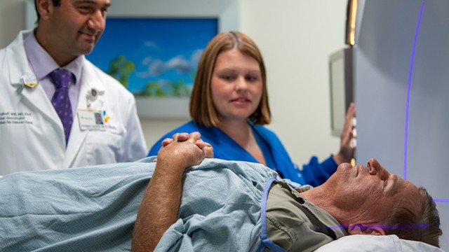 Patient lying on a bed with a doctor and nurse standing behind him