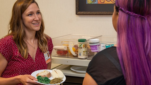 Dietitian discussing healthy eating portions with a patient, while holding a plate of food.
