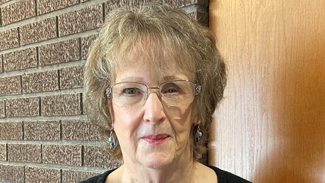 Woman looking at the camera with a brick wall behind her