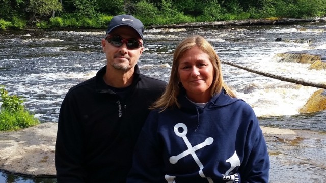 Man and woman standing in front of a short waterfall in a river