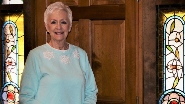 Older woman standing in front of a door, smiling