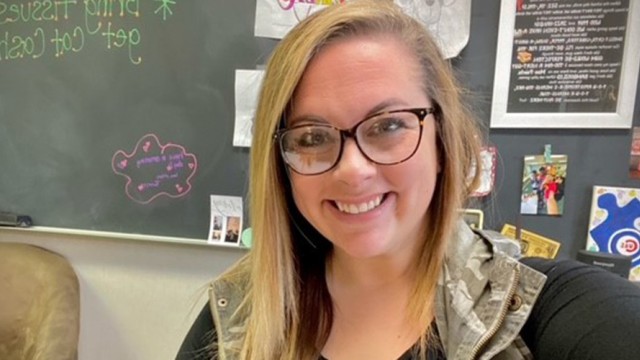 Woman smiling with a classroom chalkboard in the background