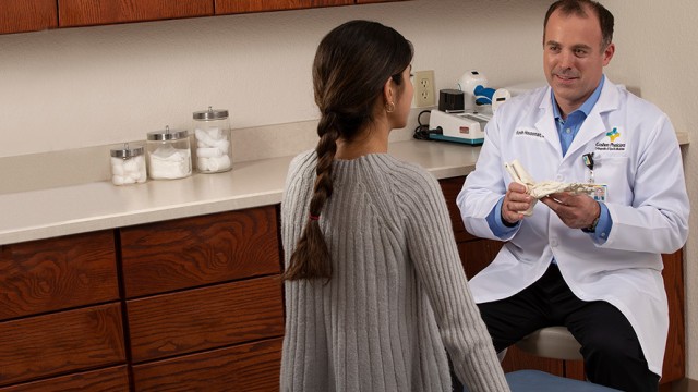 Doctor showing a patient a model of a foot skeleton