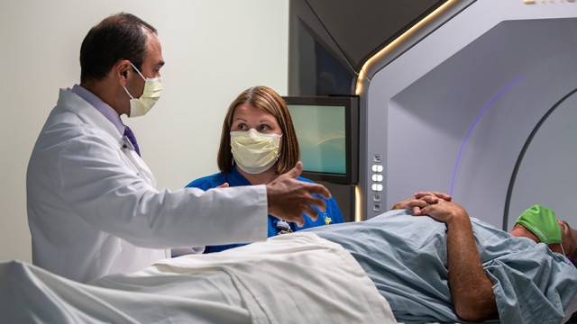 Doctor and nurse wearing masks while preparing to move a patient into an Ethos radiation machine