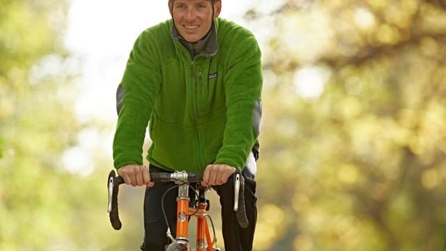 Man wearing a helmet riding a bike with trees in the background