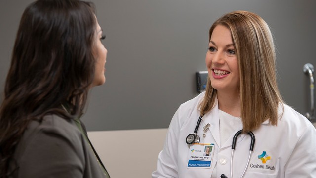 Female doctor with a stethoscope around her neck is smiling at a patient