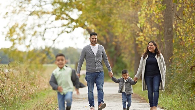 Man and woman with two small boys walking along a pathway surrounded by nature