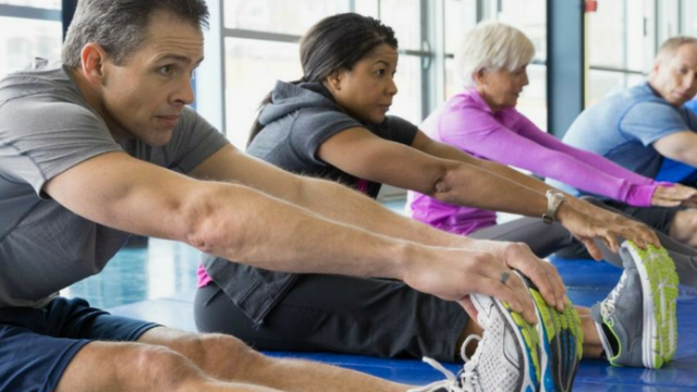 People sitting next to each other while grabbing their feet to stretch