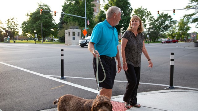 Couple walking a dog in a downtown area intersection