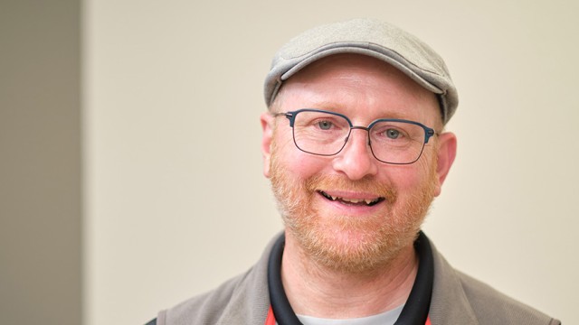 Man with a cap and glasses, smiling