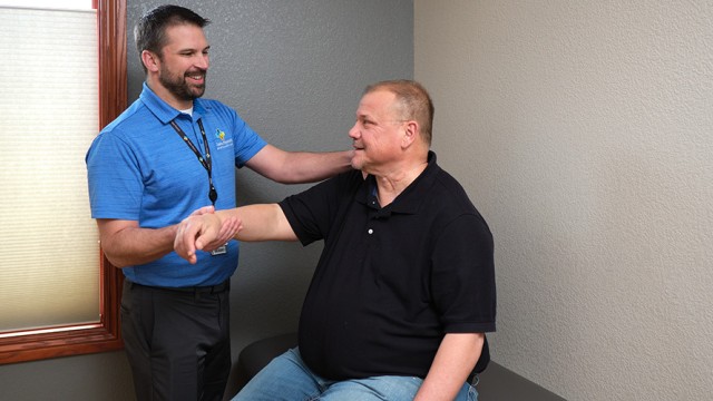 Doctor standing by a patient while examining his arm