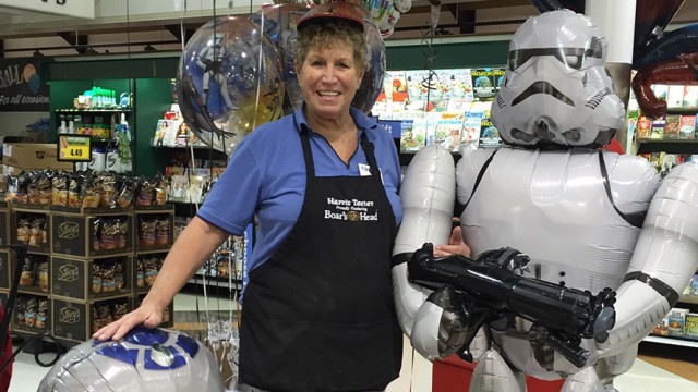 Woman with an apron standing in a toy store next to a robot