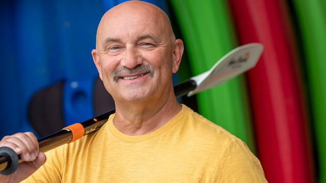 Man smiling with a kayak paddle over his shoulder