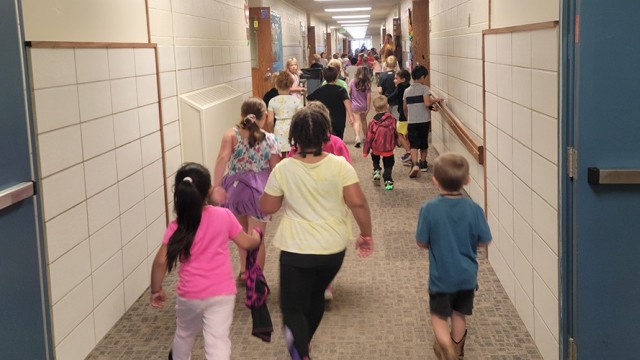Children and teacher running in a school hallway