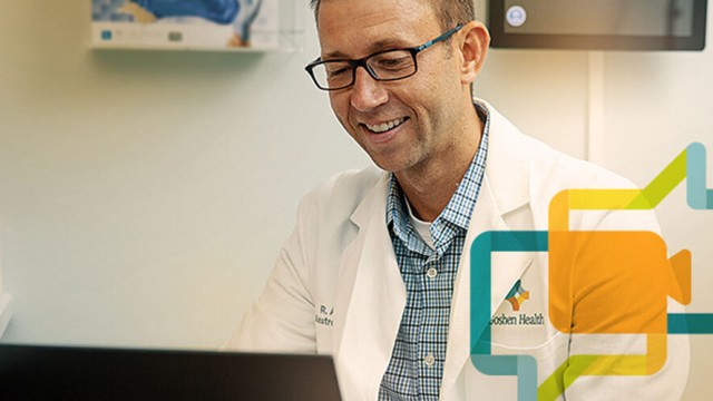 Doctor smiling while looking at his computer.