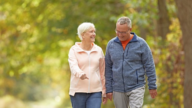 Elderly couple smiling and walking shoulder to shoulder
