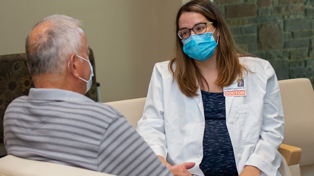 Doctor and patient with masks sitting in chairs facing each other
