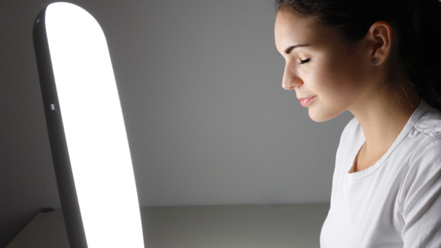Woman sitting in front of a light therapy device