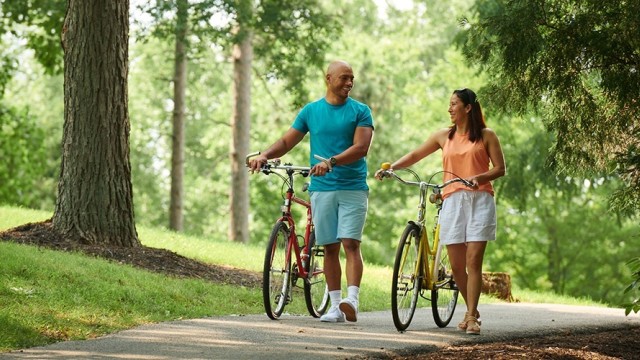 Couple talking while walking their bikes in a park