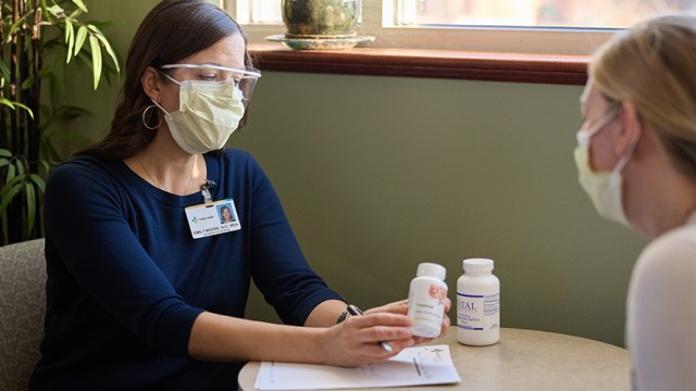 Two women sitting across from each other at a table with masks on