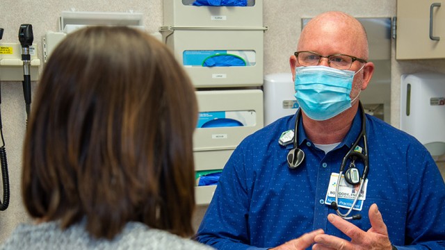 Doctor with stethoscope facing a patient in an examination room