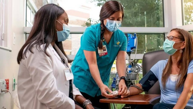 Two nurses sit with a patient getting a procedure