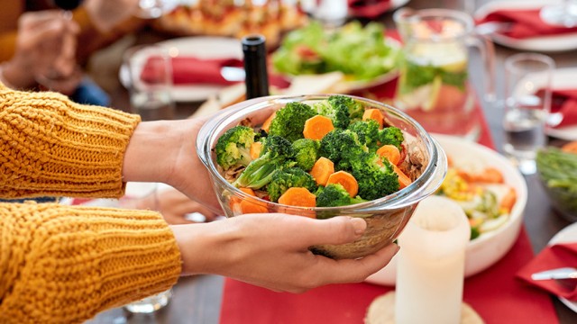 Hands placing a full salad bowl on a table full of food