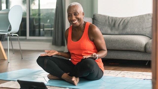 Older woman smiling while sitting on the floor in a yoga pose