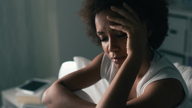 Woman sitting up in bed, holder her head