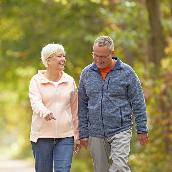 Elderly couple smiling and walking shoulder to shoulder