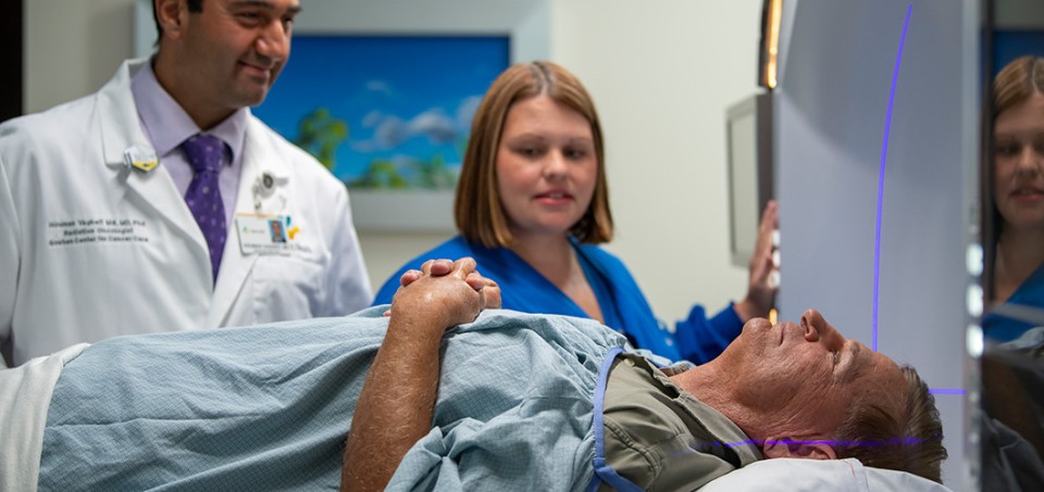 Patient lying on a bed with a doctor and nurse standing behind him