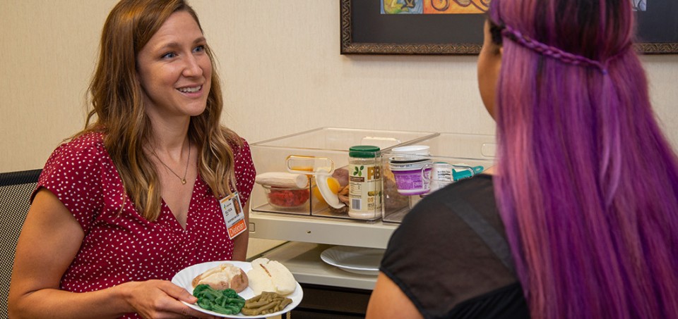 Dietitian discussing healthy eating portions with a patient, while holding a plate of food.