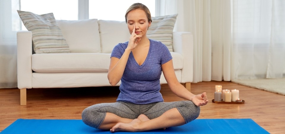 Woman sitting in yoga pose with her finger beside her nose