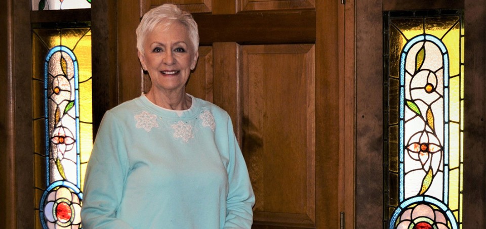 Older woman standing in front of a door, smiling