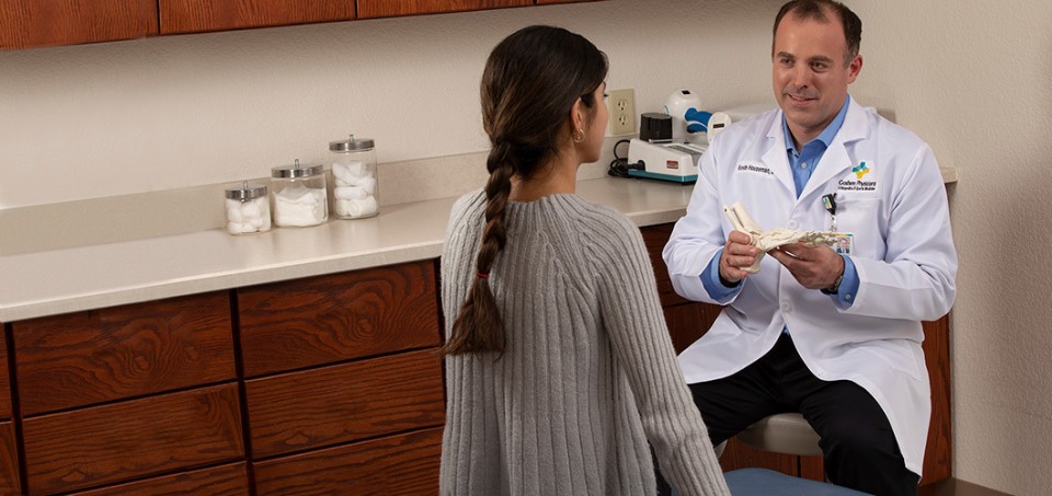 Doctor showing a patient a model of a foot skeleton