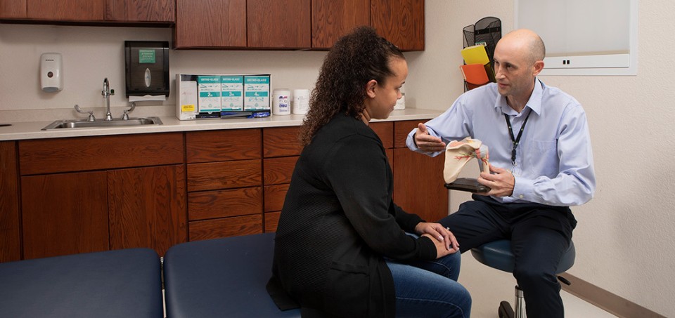 Doctor talking to patient about a model of a shoulder