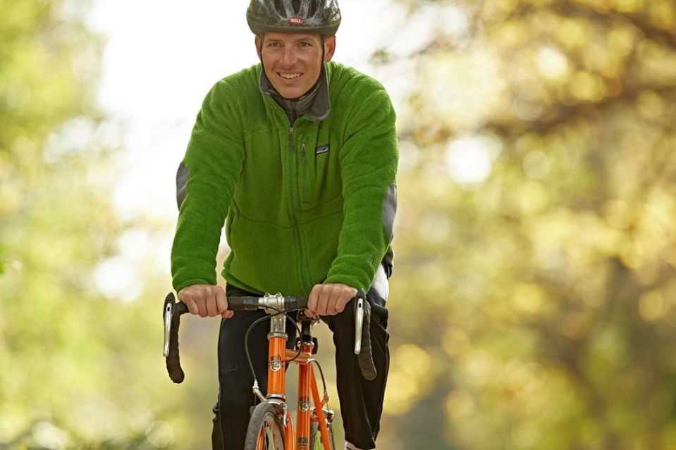 Man wearing a helmet riding a bike with trees in the background