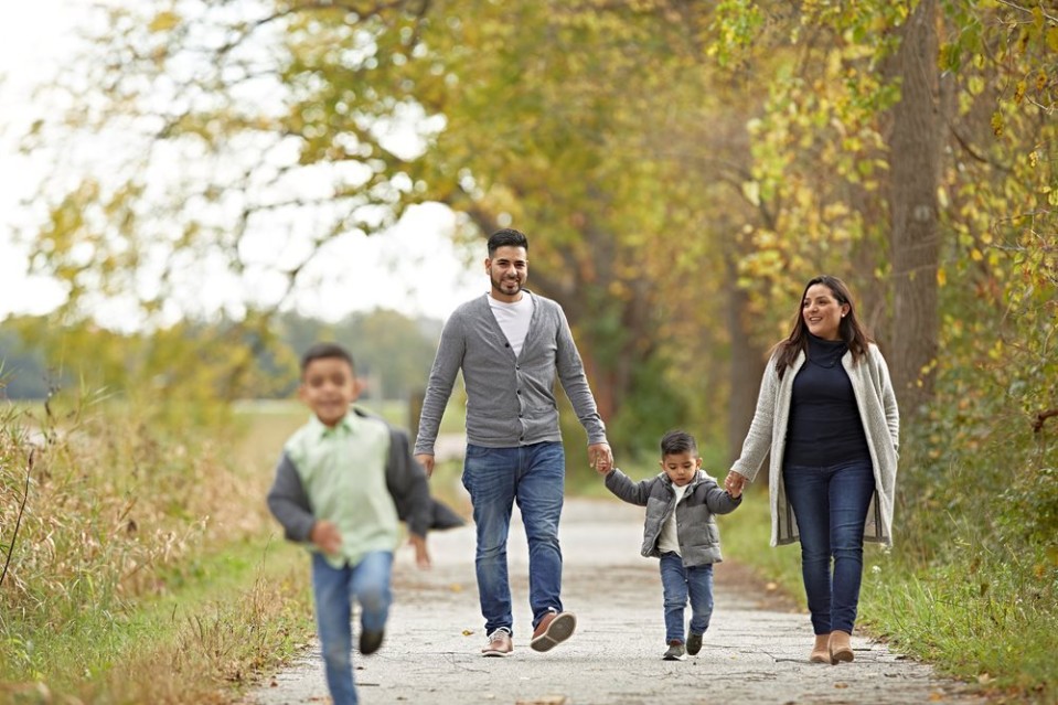 Man and woman with two small boys walking along a pathway surrounded by nature
