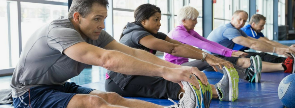 People sitting next to each other while grabbing their feet to stretch
