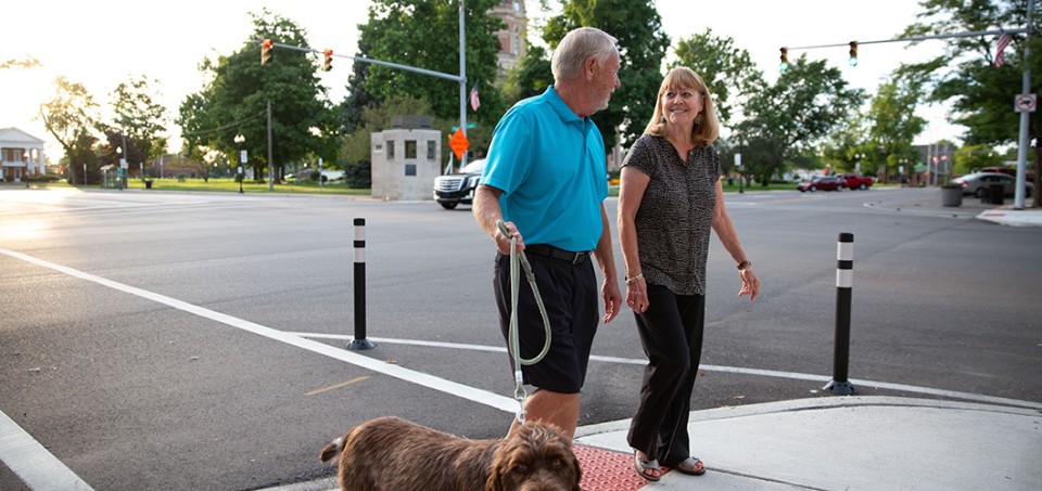 Couple walking a dog in a downtown area intersection